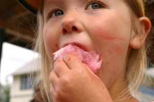 Young girl eating pink candy