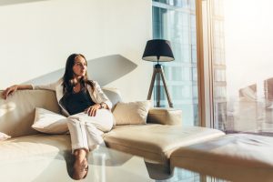 Portrait of successful businesswoman wearing elegant formal suit sitting on leather sofa relaxing after work at home