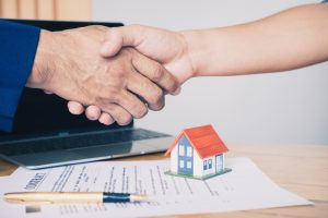 real estate agent shaking hands to his client after signing contract agreement in office,concept for real estate, moving home or renting property