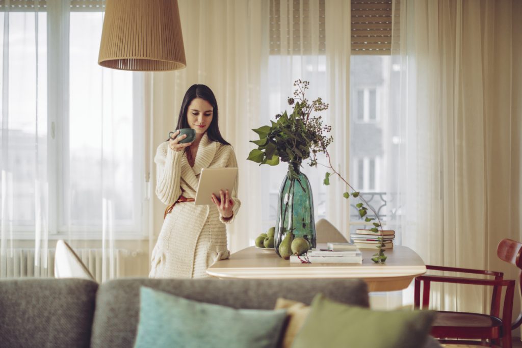 elegant women holding her cup of coffee and reading her ipad