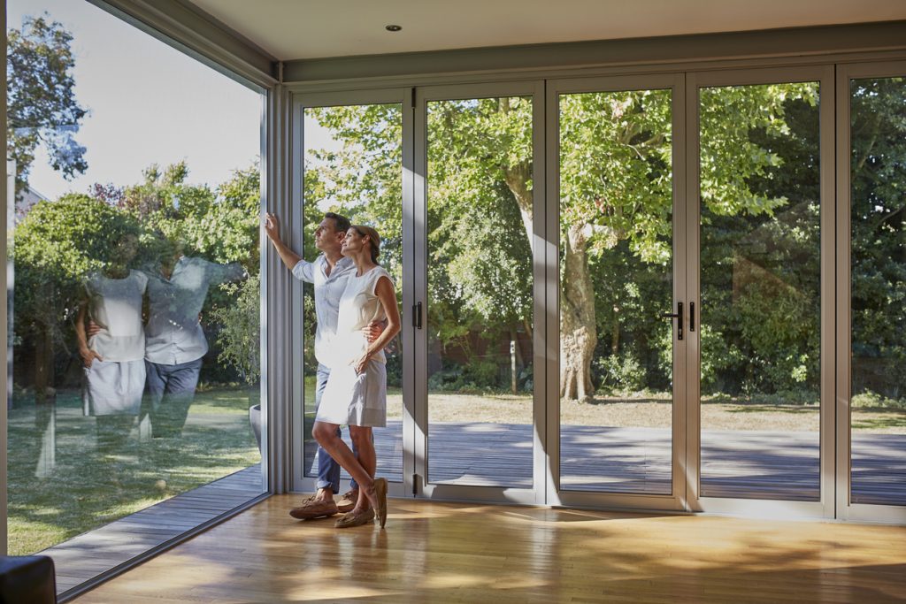 Loving couple looking through the glass window of their lovely home